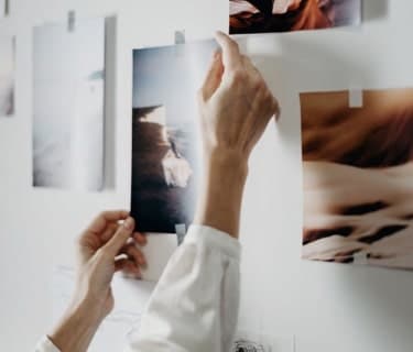 Hands adjusting photos taped to wall