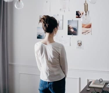 Woman looking at photos taped to wall